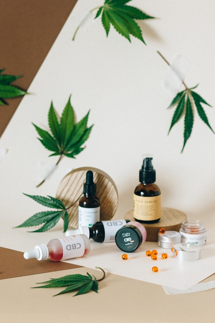 Assorted CBD oil bottles and capsules with cannabis leaves arranged aesthetically on neutral tones.